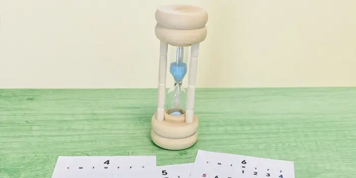 テーブルに置かれた砂時計とカレンダーの画像