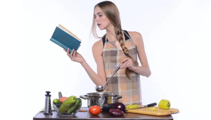 本を読みながら料理をする女性