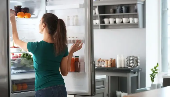 冷蔵庫を開けている緑の服を着た女性