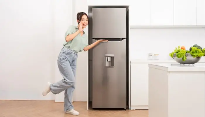 冷蔵庫の横で片足で立っている女性