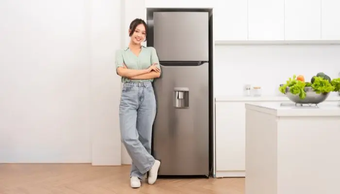 冷蔵庫の横に立っている女性