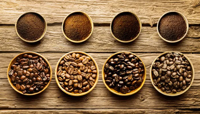 木のテーブルの上にあるコーヒー豆4種類と粉