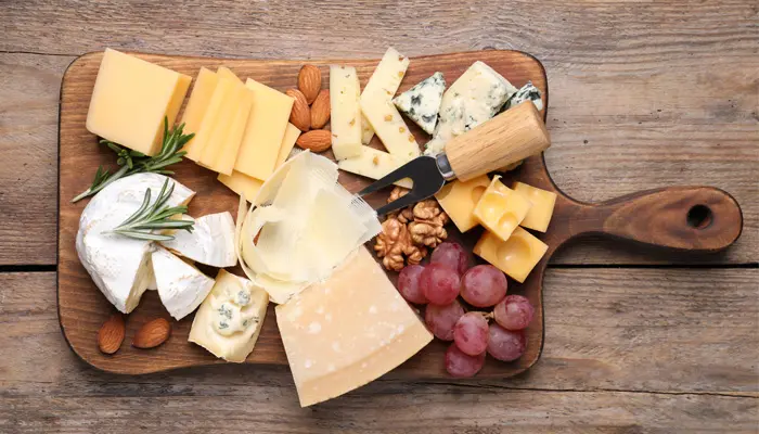 まな板の上にのっているチーズやブドウ
