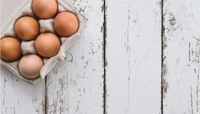 白く塗られた木の板の上にある6個入り卵パック