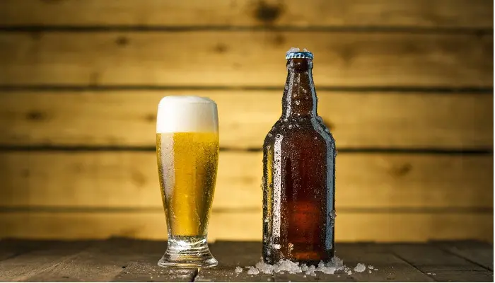 泡立ったビールが入っているグラスとビール瓶