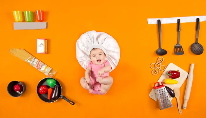 オレンジの背景に赤ちゃんと様々な野菜や調理器具