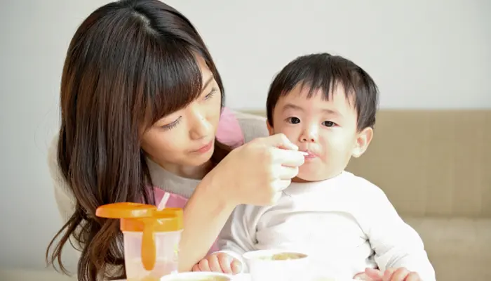 女性に離乳食を食べさせられている赤ちゃん