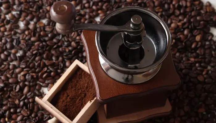 大量のコーヒー豆の上にあるコーヒーミル